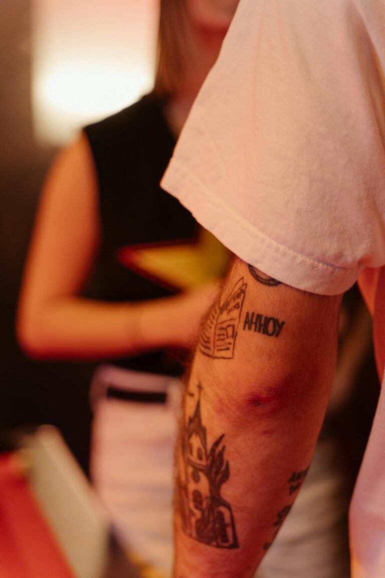 Close-up shot of a tattooed arm with visible tattoos indoors, showcasing unique designs.