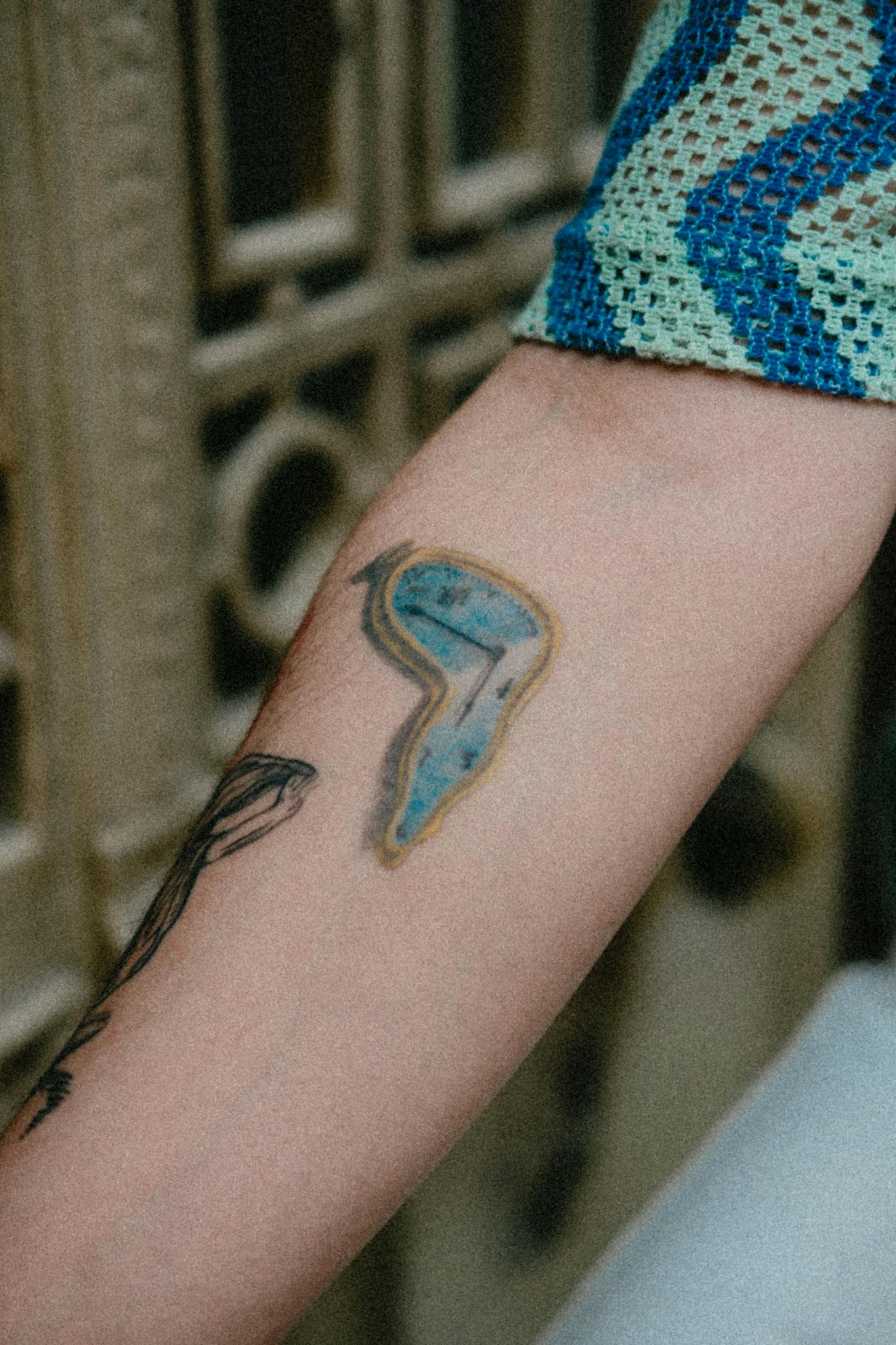 Detailed view of two unique artistic tattoos on a forearm.